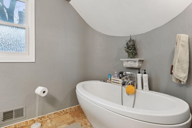 bathroom with lofted ceiling and a bath