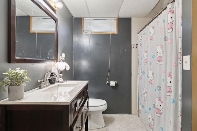 bathroom with tile patterned flooring, vanity, walk in shower, toilet, and a drop ceiling