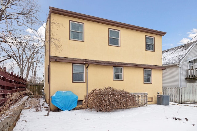 snow covered rear of property featuring central AC