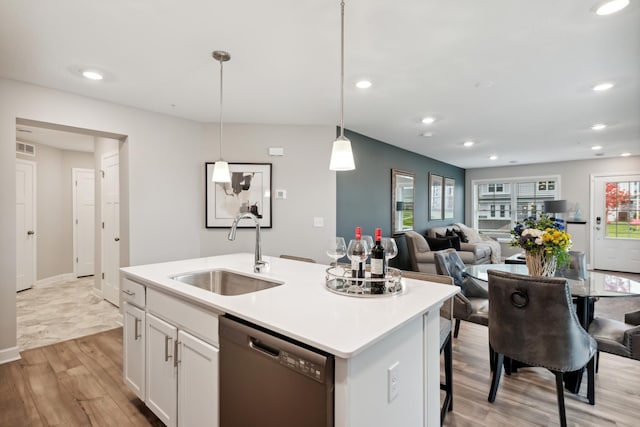 kitchen featuring sink, black dishwasher, an island with sink, white cabinets, and decorative light fixtures