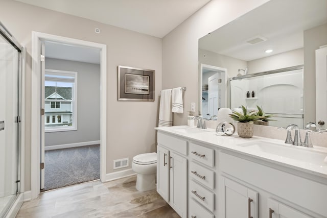 bathroom with vanity, a shower with door, and toilet