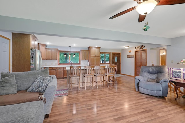 living room featuring ceiling fan, sink, and light wood-type flooring