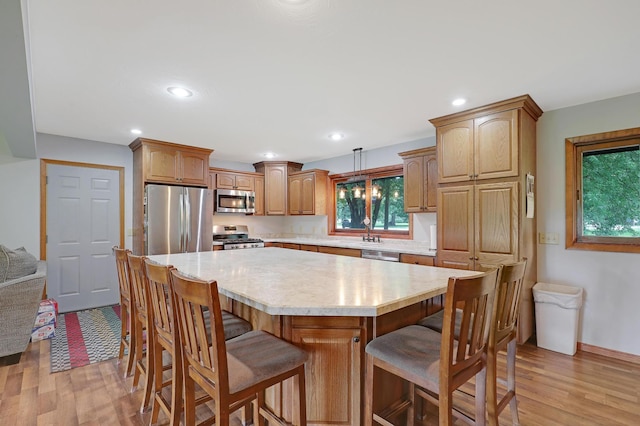 kitchen featuring a kitchen bar, light hardwood / wood-style floors, a center island, and appliances with stainless steel finishes