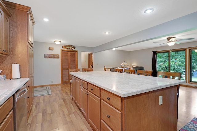 kitchen featuring ceiling fan, stainless steel dishwasher, light hardwood / wood-style floors, and a kitchen island