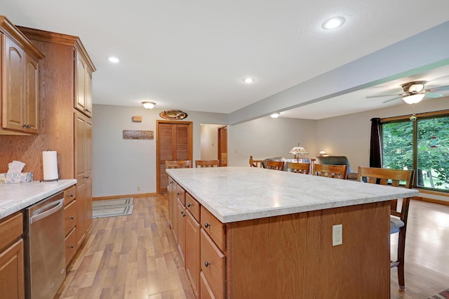 kitchen with a center island, dishwasher, light hardwood / wood-style floors, and a breakfast bar area