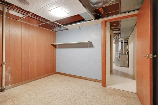 basement featuring heating unit and wood walls