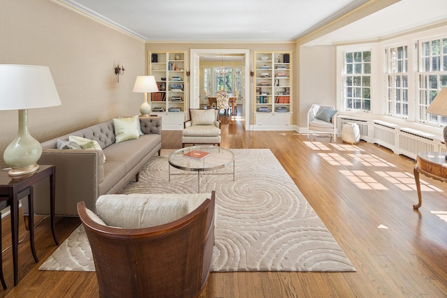 living room with radiator heating unit, built in features, ornamental molding, and light hardwood / wood-style floors