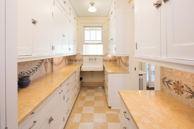 interior space with white cabinetry, sink, and tasteful backsplash