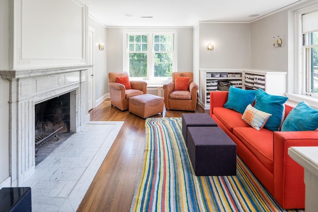 living room featuring ornamental molding, radiator, a high end fireplace, and light hardwood / wood-style flooring