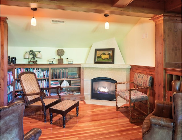 sitting room with hardwood / wood-style flooring, vaulted ceiling with beams, and a large fireplace