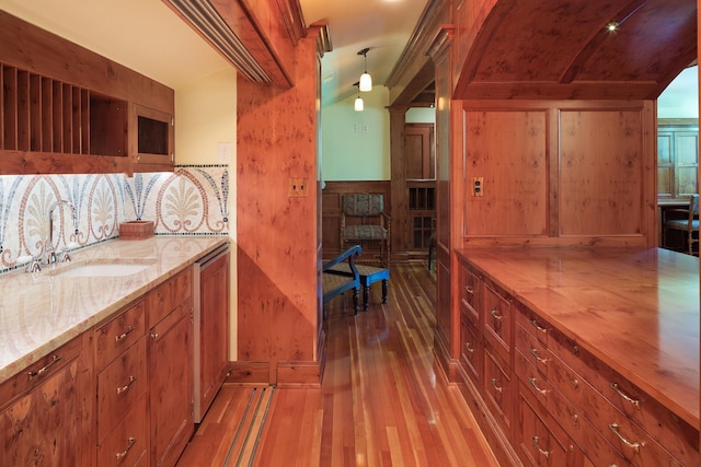 kitchen featuring sink, dark wood-type flooring, hanging light fixtures, wood counters, and ornate columns