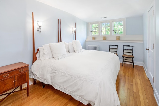 bedroom with radiator and light hardwood / wood-style floors