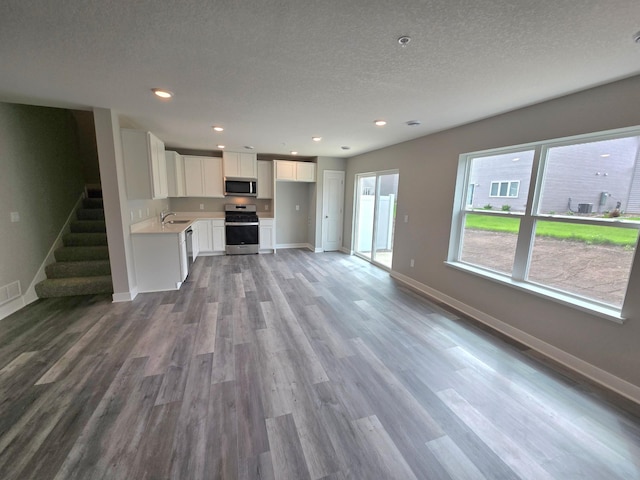 13647 Kaylemore Trl, Rosemount, MN 55068 - unfurnished living room with wood finished floors, a textured ceiling, recessed lighting, and stairs