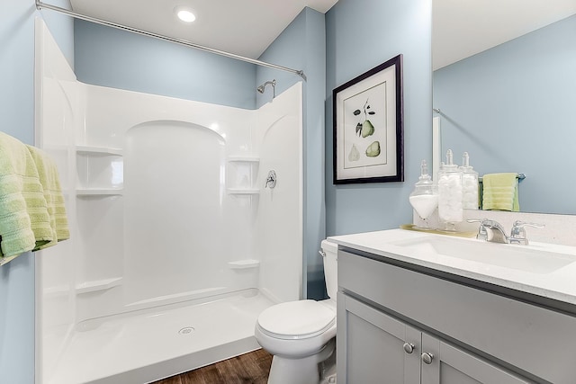 bathroom with a shower, wood-type flooring, vanity, and toilet