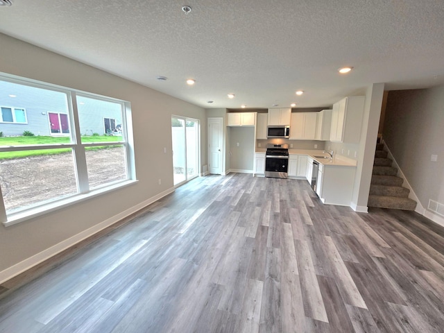 13651 Kaylemore Trl, Rosemount, MN 55068 - unfurnished living room with a textured ceiling, light wood finished floors, stairway, and recessed lighting