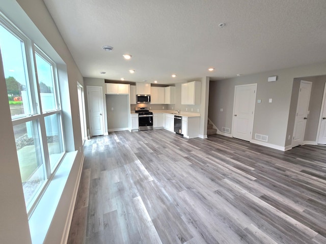 13651 Kaylemore Trl, Rosemount, MN 55068 - unfurnished living room featuring plenty of natural light, a textured ceiling, light wood-type flooring, recessed lighting, and stairway
