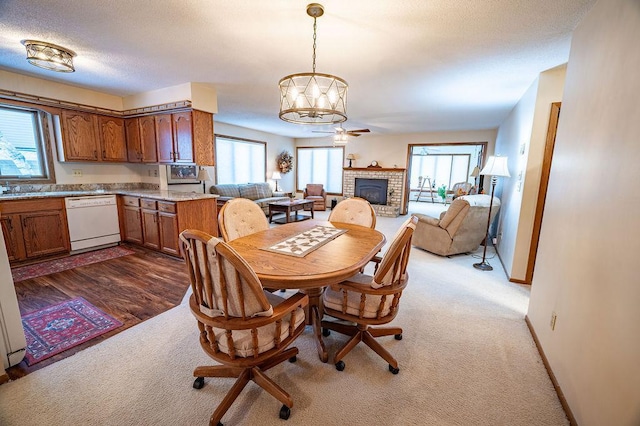 carpeted dining area with sink, ceiling fan with notable chandelier, a fireplace, and a textured ceiling