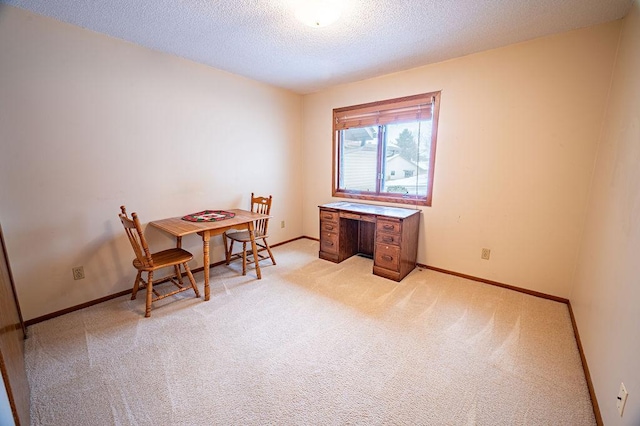 carpeted home office featuring a textured ceiling