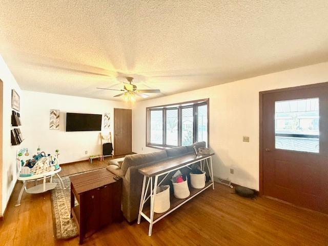 living room with hardwood / wood-style floors, a textured ceiling, and ceiling fan