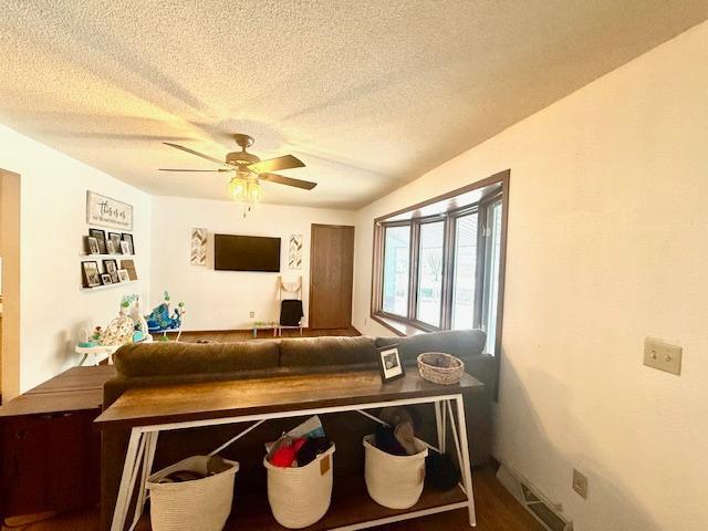 living room with a ceiling fan and a textured ceiling