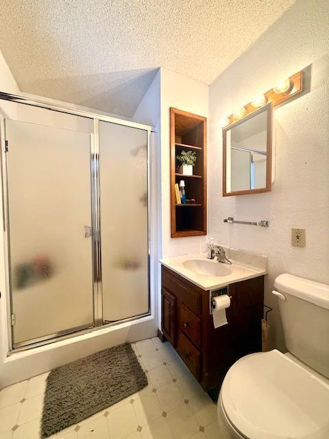 full bathroom featuring toilet, a textured ceiling, and a shower stall