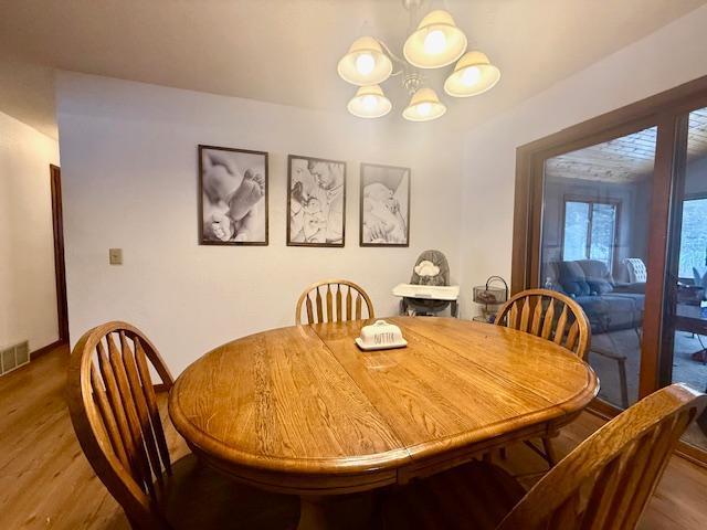 dining area with a notable chandelier, wood finished floors, and visible vents