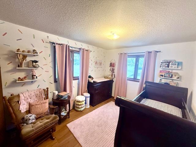 bedroom featuring a textured ceiling, multiple windows, and wood finished floors