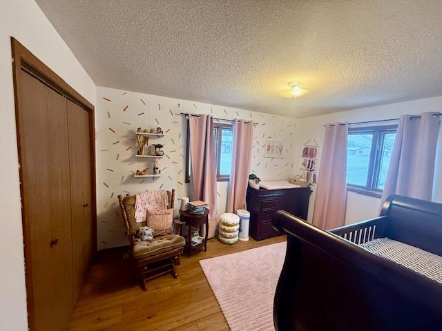 bedroom featuring a closet, light wood-style flooring, a textured ceiling, and multiple windows