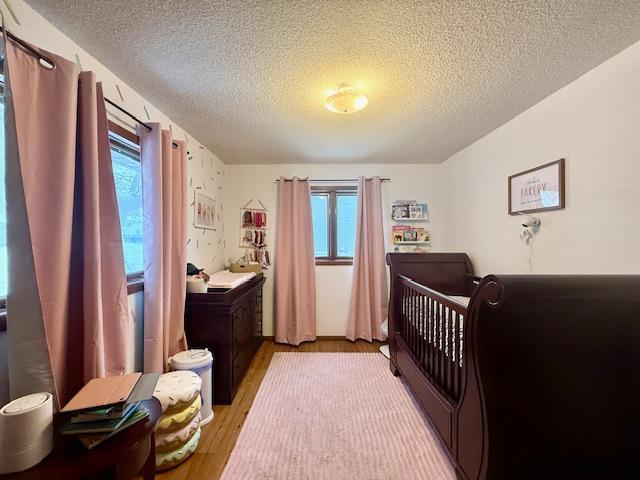 bedroom featuring multiple windows, light wood finished floors, and a textured ceiling