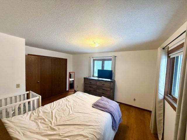 bedroom featuring baseboards, a textured ceiling, wood finished floors, and a closet