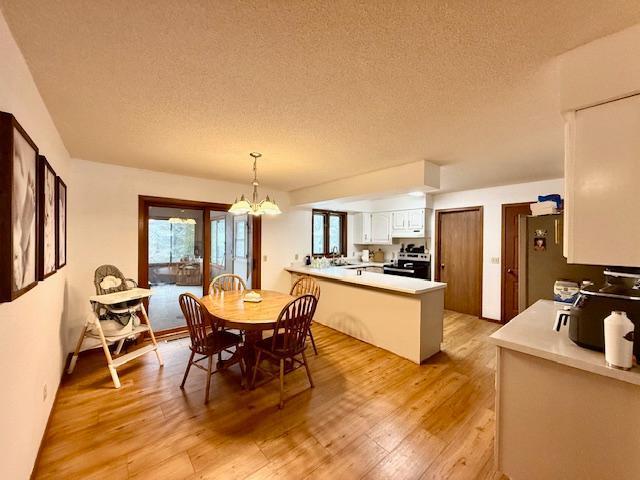 dining space featuring a textured ceiling, a chandelier, and light wood-style floors