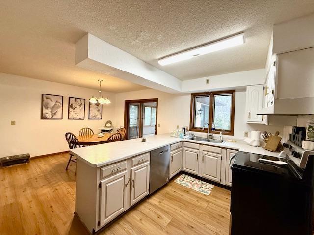 kitchen with a peninsula, range with electric stovetop, a sink, dishwasher, and a notable chandelier