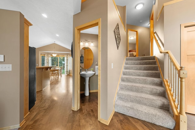 stairway featuring hardwood / wood-style floors and vaulted ceiling