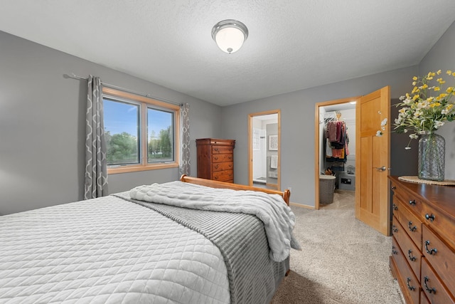 carpeted bedroom with a walk in closet, a textured ceiling, and a closet