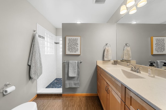 bathroom featuring vanity, hardwood / wood-style floors, toilet, and tiled shower