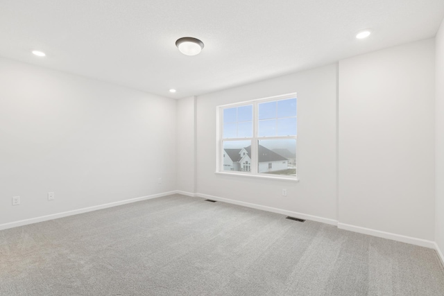 carpeted empty room featuring recessed lighting, visible vents, and baseboards