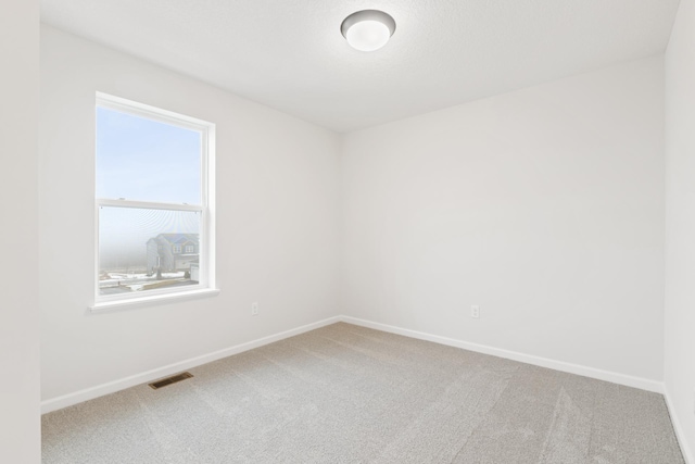 spare room featuring carpet floors, visible vents, and baseboards