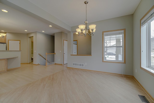 empty room with an inviting chandelier, light hardwood / wood-style floors, and a wealth of natural light