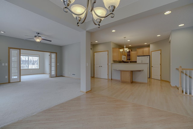 unfurnished living room with ceiling fan with notable chandelier and light wood-type flooring