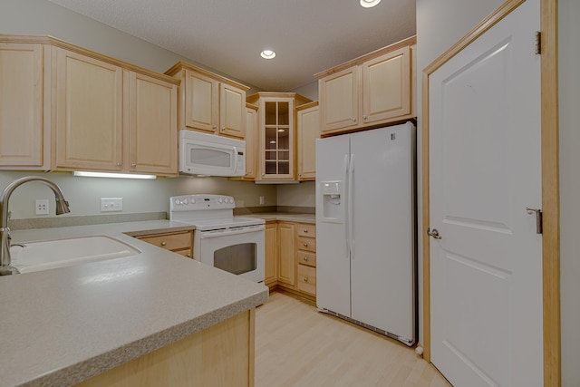 kitchen featuring white appliances, light brown cabinetry, sink, and light hardwood / wood-style flooring