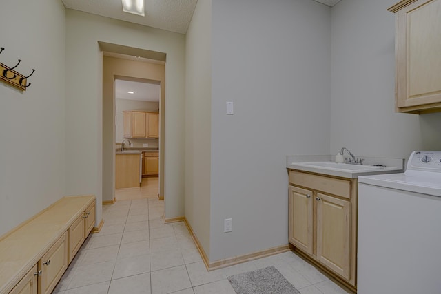 clothes washing area featuring washer / clothes dryer, sink, cabinets, and light tile patterned floors