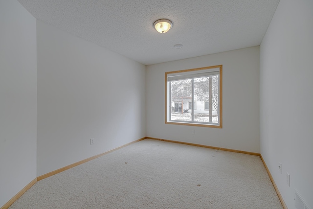 carpeted empty room with a textured ceiling