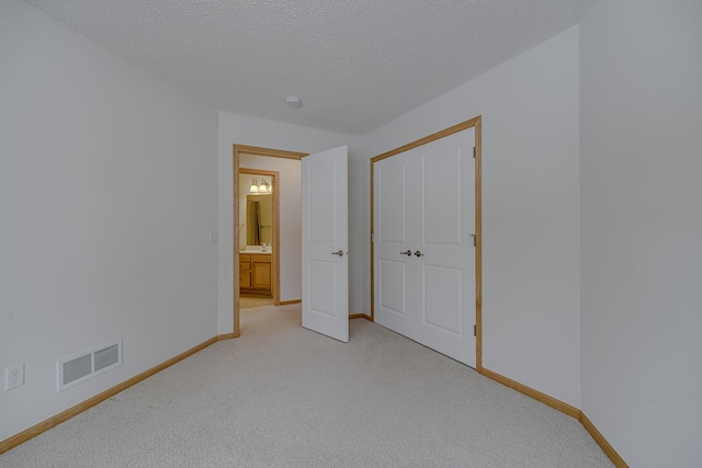 unfurnished bedroom with light colored carpet, a closet, and a textured ceiling