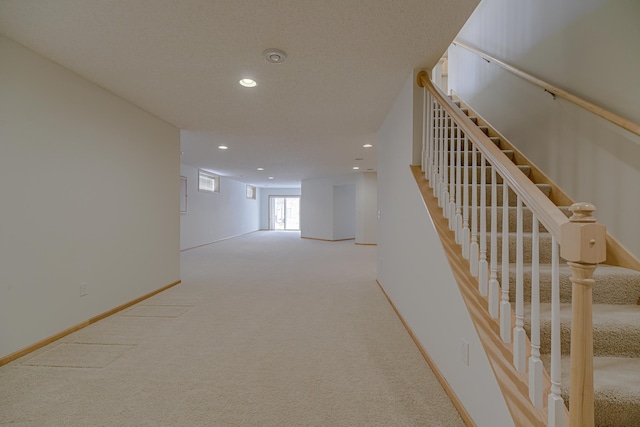 hall with light carpet and a textured ceiling