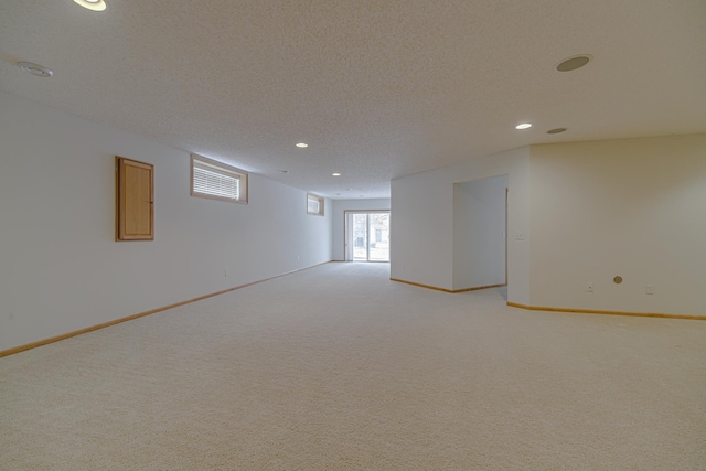 basement featuring light colored carpet and a textured ceiling