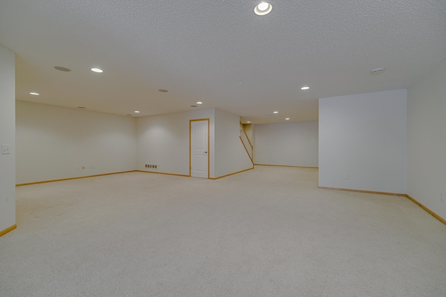 unfurnished room with light colored carpet and a textured ceiling