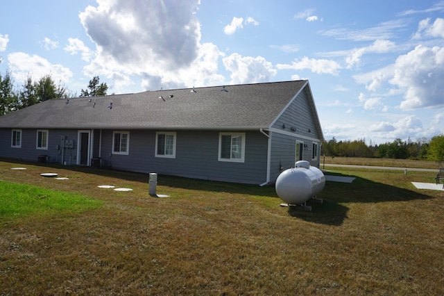 rear view of house featuring cooling unit, roof with shingles, and a yard