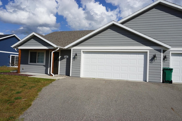 ranch-style house with an attached garage, aphalt driveway, and roof with shingles