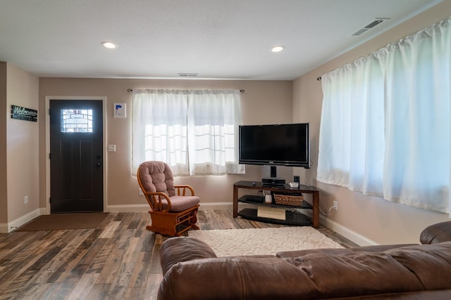 living room featuring baseboards, visible vents, wood finished floors, and recessed lighting