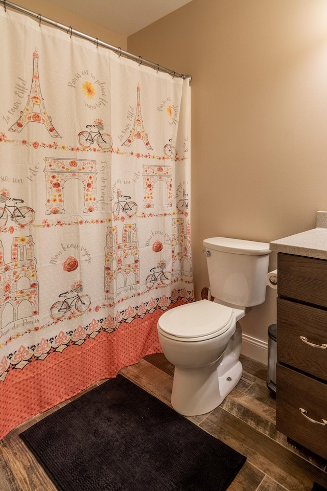 bathroom with baseboards, toilet, wood finished floors, curtained shower, and vanity